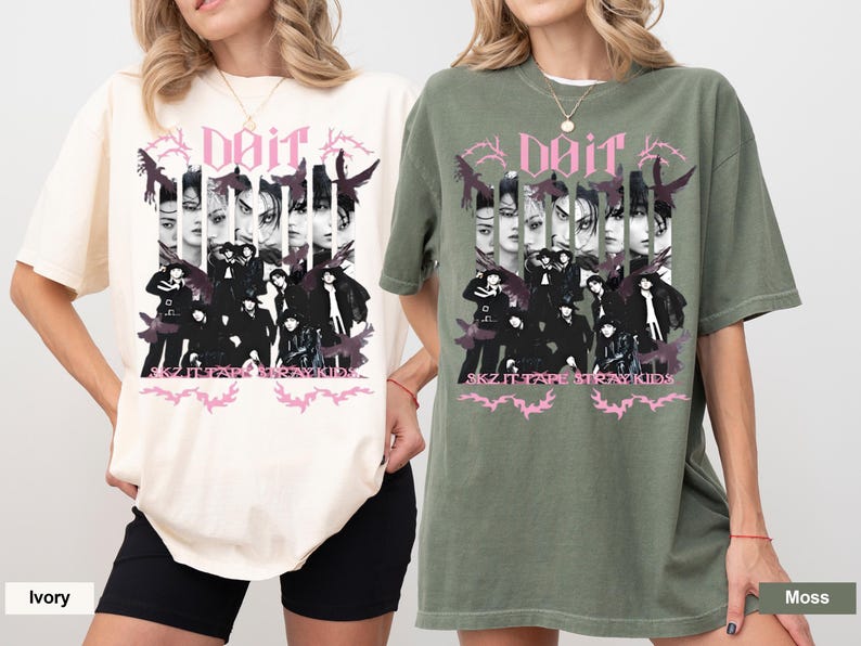 Pu&ograve; includere: T-shirt avorio e verde muschio con un design grafico. Il design presenta il testo "doir" e "SKZ IT TAPE STRAY KIDS", insieme a immagini di persone ed elementi decorativi in nero e rosa.