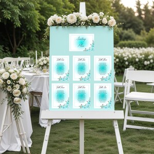 May include: A light blue wedding seating chart on a white easel, decorated with white roses and blue floral accents. The chart displays the text "Seating Plan" and six tables with guest names.