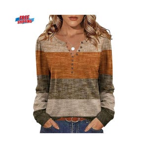 Könnte beinhalten: Ein langärmliges Hemd mit Henley-Ausschnitt und Colorblock-Design. Das Hemd hat horizontale Streifen in den Farbtönen Beige, Orange, Olivgrün und Grau. Es hat eine Knopfleiste und eine gerippte Manschette. Das Hemd ist aus einem weichen, bequemen Material.