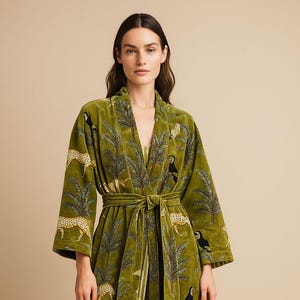 Könnte beinhalten: Olivgrüner Samtrobe mit Bindegürtel. Die Robe hat ein sich wiederholendes Muster aus Leoparden, Tukanen und Palmen. Die Robe hat weite Ärmel und ein Wickeldesign.