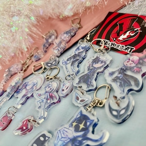 Peut inclure: Collection de porte-clés en acrylique transparent avec des personnages de style anime. Chaque porte-clés est doté d'un fermoir argenté. Les porte-clés présentent divers personnages et motifs de masques, avec un logo rouge et noir en arrière-plan.