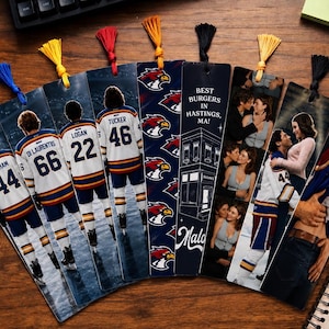 May include: A collection of decorative bookmarks with colorful tassels. Some feature hockey players in jerseys with numbers and names, while others display romantic images and the text "Best Burgers in Hastings, MA!"