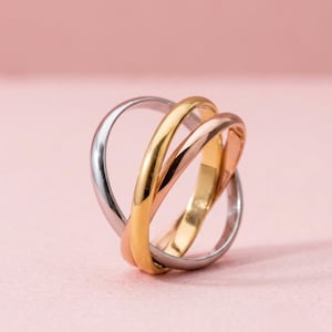 Pode incluir: Um anel de três bandas entrelaçadas em ouro amarelo, ouro rosa e metal prateado polido. As bandas lisas e arredondadas estão entrelaçadas para criar uma estrutura contínua e fluida com um acabamento metálico altamente reflexivo.