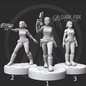 May include: Three 3D-printed figurines of a female character in a futuristic outfit, each holding a weapon. The figures are in a neutral color, standing on circular bases. The Dark Fire Designs logo is visible in the background.