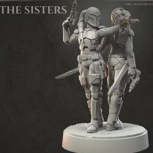 Könnte beinhalten: Graue Figur von zwei gepanzerten Figuren, die jeweils eine Blasterpistole halten. Eine Figur hat einen Helm mit Hörnern. Beide Figuren haben Schwerter an ihren Seiten. Der Sockel ist rund und weiß, mit dem Text "THE SISTERS" oben.