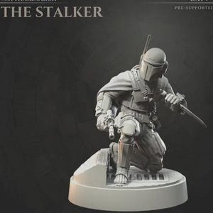 Könnte beinhalten: Detaillierte, graue Figur einer knienden Figur mit Helm und Rüstung, die eine Waffe hält. Die Figur steht auf einem kreisförmigen Sockel. Der Text oben lautet "THE STALKER" und "PRE-SUPPORTED".