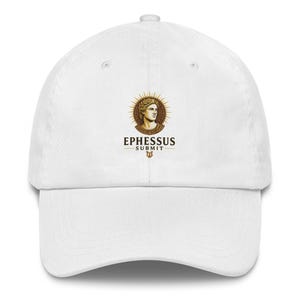 Op de afbeelding: Witte baseballpet met een goud en bruin embleem met een lauwerkrans en de tekst "EPHESSUS SUBMIT". De pet heeft een gebogen klep en een verstelbare band. Een casual accessoire.