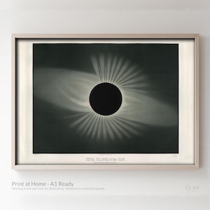May include: Framed print of a total solar eclipse, featuring a dark central circle surrounded by radiating light. The print is in black and white, with the text "TOTAL ECLIPSE of the SUN" at the bottom. The frame is light-colored wood.