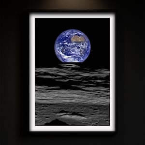 Könnte beinhalten: Gerahmter Druck mit der Erde, ihren blauen Ozeanen und Kontinenten, vor einem schwarzen Weltraumhintergrund. Die Erde befindet sich über einer strukturierten, grauen Mondoberfläche. Der Druck enthält den Text "Print at Home" und "ÉLAN PRINTS".