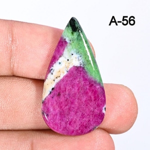 Könnte beinhalten: Ein tropfenförmiger Edelstein mit einer lebendigen Farbmischung. Der Stein hat eine tiefmagentafarbene Basis, akzentuiert mit Bändern aus Weiß, Grün und Schwarz. Der Text "A-56" ist in Schwarz oben rechts aufgedruckt.