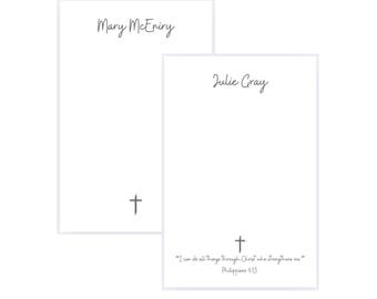 May include: Two white notepads with handwritten names and a cross symbol. One notepad reads "Mary McEniry" and the other reads "Julie Gray" with a Bible verse: "I can do all things through Christ who strengthens me" Philippians 4:13.