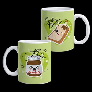 May include: Two white ceramic mugs with a light green background. One mug features a cartoon image of a slice of toast with a smiling face, and the other mug has a cartoon jar of chocolate spread. Both mugs have the text "better together".