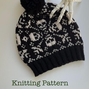 May include: Black and white knit hat with a skull pattern and a black pom-pom. The hat features a repeating design of white skulls on a black background. The text "Knitting Pattern" is at the bottom of the image.