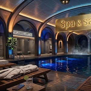 Può includere: Una spa e sauna interna con piscina, sedie a sdraio e docce. L'insegna sopra la piscina recita "Spa & sauna". La spa ha un design lussuoso e moderno con soffitti a volta e illuminazione ambientale. L'acqua della piscina è di un blu intenso.