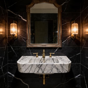 May include: An opulent bathroom with a marble sink and gold taps, set against a black marble wall with white veining. A gold-framed mirror and two wall lights with warm illumination enhance the luxurious feel.