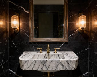 May include: A luxurious bathroom featuring a marble sink with gold fixtures, set against a black marble wall with white veining. A gold-framed mirror and two sconces with glowing lights complete the elegant design.