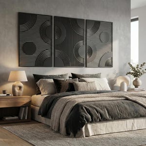Könnte beinhalten: Ein modernes Schlafzimmer mit einem Bett mit einer dunkelgrauen Bettdecke und einer beigefarbenen Strickdecke. Über dem Bett sind drei schwarze Wandpaneele mit kreisförmigen und halbkreisförmigen Designs angebracht. Ein Nachttisch aus Holz mit einer Lampe und Büchern steht neben dem Bett.