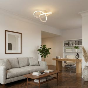 Peut inclure: Un plafonnier blanc de forme abstraite est monté au plafond. Le luminaire a un design incurvé et en boucle. La pièce comprend un canapé gris, une table basse en bois et une œuvre d'art encadrée. Un bureau et une bibliothèque sont également visibles.