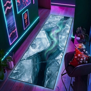 May include: A rectangular rug with a design resembling a cracked ice surface with a vibrant aurora borealis effect. The rug features shades of blue, green, and purple, creating a visually striking and unique floor covering.