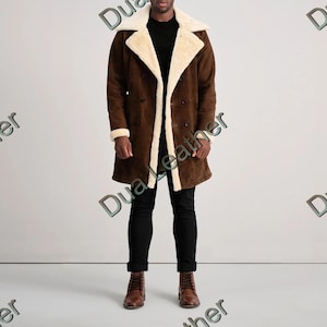 Puede incluir: Un abrigo de ante marrón con forro y cuello de borreguillo color crema. El abrigo cruzado es largo, con ribete de borreguillo color crema en los puños y en la parte delantera. La persona lleva pantalones negros y botas marrones.