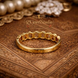 Vintage inspired hexagon wedding band with round stones in gold setting, photographed on ornate textured surface highlighting Art Deco design details