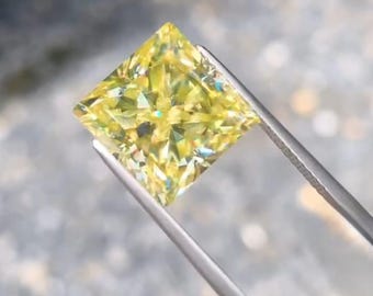 May include: A square-cut, yellow diamond is held by silver tweezers. The gemstone's facets reflect light, creating a sparkling effect. The diamond's colour is a vibrant, light yellow. The tweezers are made of metal.