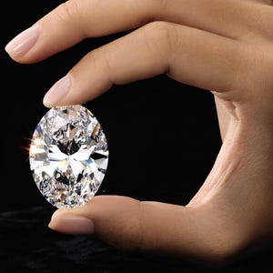 May include: A large, oval-cut diamond with brilliant facets, held between two fingers against a black background. The diamond sparkles, reflecting light. The image highlights the clarity and cut of the gemstone, showcasing its brilliance.