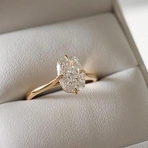 Op de afbeelding: Een gouden ring met een enkele rechthoekige diamant in radiant-slijpvorm, vastgehouden door vier klauwen. De ringband is glad en gepolijst en toont een klassiek ontwerp met een heldere, gefacetteerde edelsteen die het licht reflecteert.