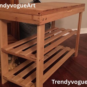 May include: A light brown bamboo shoe rack with a slatted design and a hinged top. The rack has three shelves for shoe storage and is suitable for an entryway or closet. The text "TrendyvogueArt" is visible.