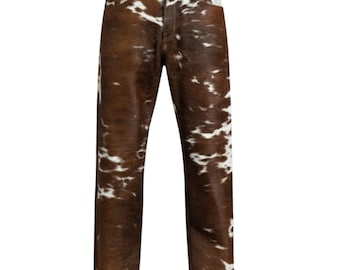 May include: Cowhide-patterned jeans in brown and white. The pants have a classic five-pocket design with a button and zipper closure. The fabric has a natural, textured appearance.