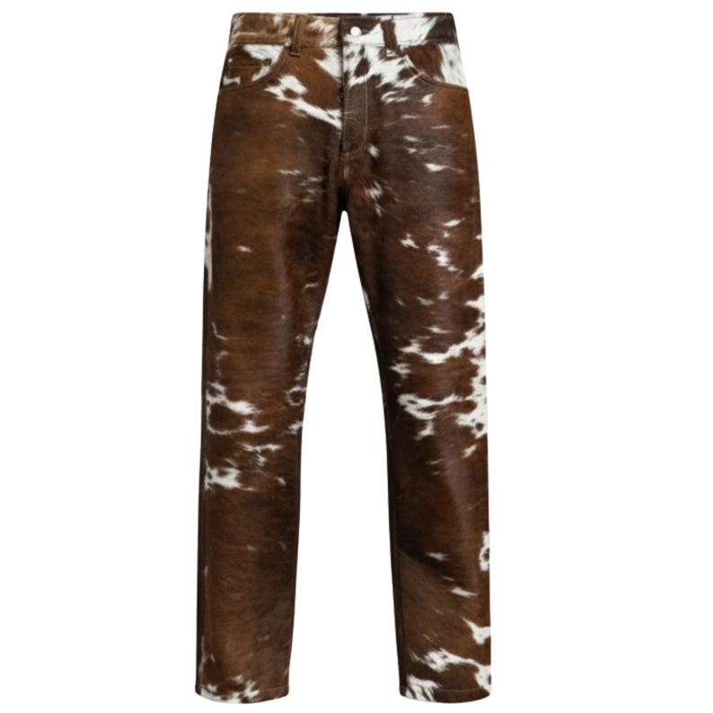 May include: Cowhide-patterned jeans in brown and white. The pants have a classic five-pocket design with a button and zipper closure. The fabric has a natural, textured appearance.