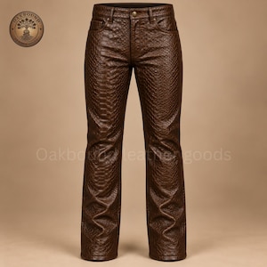 May include: Dark brown trousers featuring a textured snakeskin-like pattern throughout. The trousers include a front button closure, belt loops, and two front pockets. A circular logo in the top left corner reads Oakbound Leather Goods.