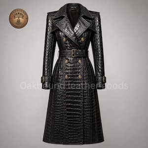 Puede incluir: Una gabardina negra con textura de piel de cocodrilo, frente de doble botonadura con botones dorados, cinturón a juego con hebilla y charreteras en los hombros. El logotipo y el texto Oakbound Leather Goods son visibles en la prenda.