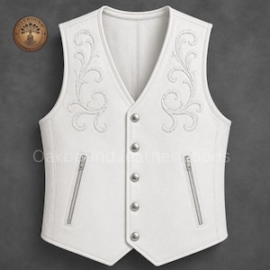 May include: A white leather vest with intricate embroidered floral designs on the front. The vest features a V-neck, silver-toned buttons, and two zippered pockets. The brand name "Oakbound Leather Goods" is visible on the upper left.