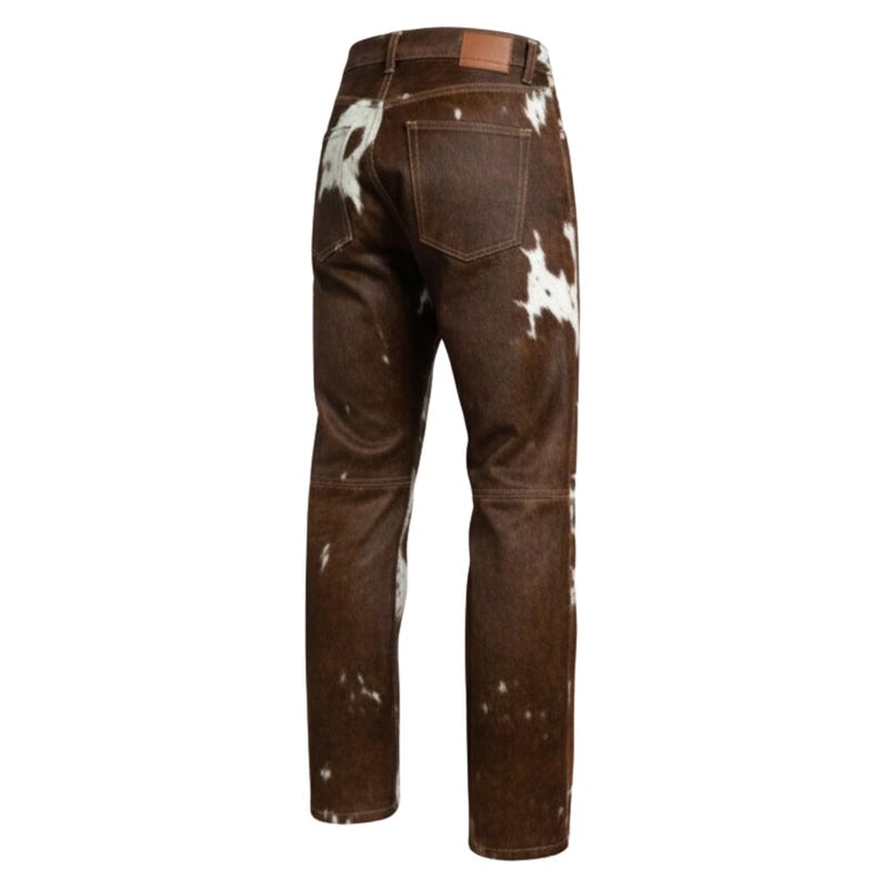 May include: Brown and white cowhide pants. The pants have a classic five-pocket design with a brown leather patch on the back. The pants are made of a brown cowhide material with white patches.
