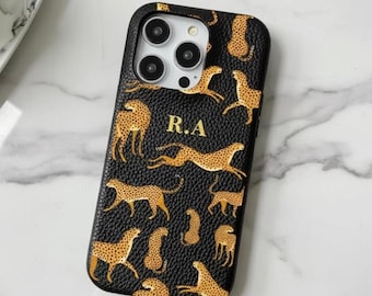 May include: Black phone case with a cheetah print design. The case features a repeating pattern of cheetahs in various poses, with gold accents. The initials "R.A" are displayed in gold. The case is designed for a smartphone.