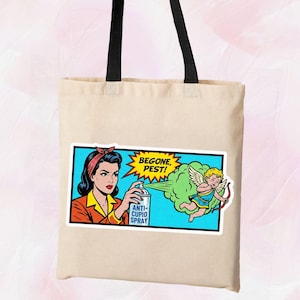 May include: A cream tote bag with a pop art style graphic. The graphic shows a woman spraying "Anti-Cupid Spray" at a cherub with a bow and arrow. The image includes the text "Begone, Pest!"