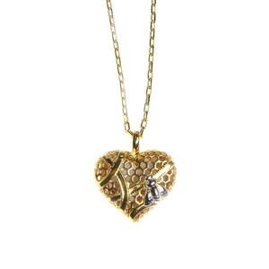 May include: A gold necklace with a heart-shaped pendant. The pendant has a honeycomb pattern and a small bee charm. The necklace is suspended from a fine chain, offering a delicate and elegant appearance.