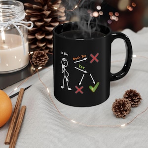 May include: A black ceramic mug with a white graphic of a stick figure and a decision-making flowchart. The text on the mug reads "If You, Don't Try, Try". The mug has a curved handle and is filled with a dark liquid.