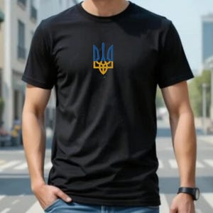May include: A black short-sleeved t-shirt featuring a centered graphic of the Ukrainian Tryzub emblem. The emblem is colored in blue and yellow, positioned on the chest area of the shirt. The garment has a standard crew neckline and short sleeves.