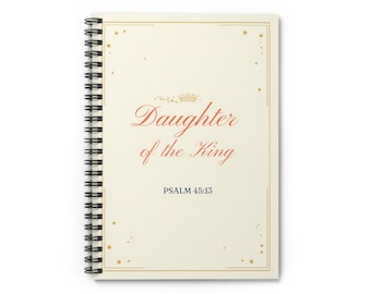 Può includere: Quaderno a spirale color crema con la scritta "Daughter of the King" in corsivo rosso, una grafica a corona e la scritta "Salmo 45:13". Il quaderno ha un bordo dorato e piccoli accenti a stella.