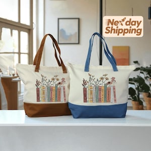 May include: Two canvas tote bags with floral and book designs. One bag has a brown base and handles, the other has a blue base and handles. The bags feature a cream-colored body with a colorful floral and book graphic.