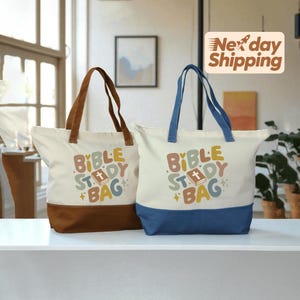 May include: Two canvas tote bags with the text "Bible Study Bag". One bag has brown handles and a brown bottom, the other has blue handles and a blue bottom. The text is in colorful, playful lettering.
