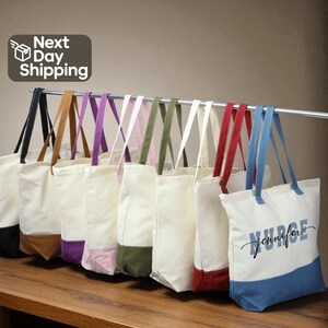 A row of colorful tote bags with various patterns and colors, including white, blue, and red, hanging on a rack.