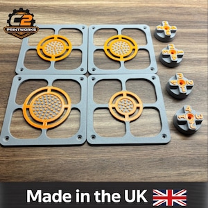 May include: Four square grey frames with orange circular centres featuring textured dots, accompanied by four small grey circular knobs with orange numbers 1 through 4 embossed on the surface. The C2 Printworks logo is visible in the top left corner.