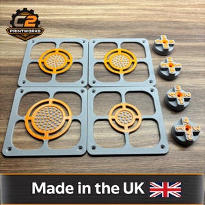 May include: A collection of grey and orange 3D-printed components. Four square frames with orange circular centres and four grey cross-shaped pieces with orange numbers are shown. The text "Made in the UK" is visible.