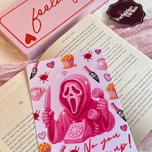 May include: Pink art print featuring a Ghostface character holding a knife and a phone, with the text "No you hang up!". The print includes hearts, popcorn, and blood splatters. A pink box with "feeling lucky" is in the background.