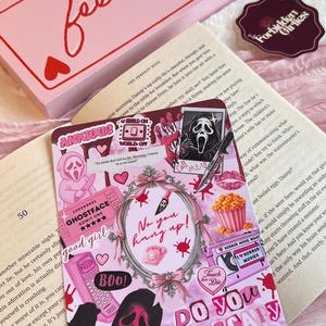 May include: A pink box with the words "feeling lucky" in red script, a sticker, and a decorative card featuring a Scream mask and the text "Do you like scary movies?" The card has pink accents and horror movie themes.