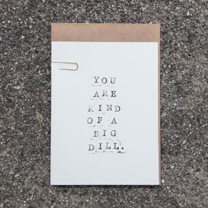 Peut inclure: Carte de vœux blanche avec le texte "YOU ARE KIND OF A BIG DILL" imprimé en noir. Un trombone doré maintient la carte fermée, à l'intérieur d'une enveloppe marron. Idéal pour une occasion spéciale.