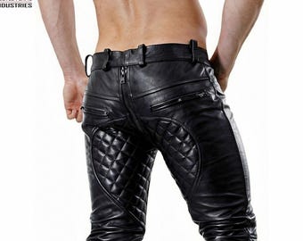 May include: Black leather pants featuring a prominent vertical zipper running down the center back, two horizontal zippered pockets, and quilted diamond-patterned panels on the seat. The garment includes belt loops and a smooth leather finish.